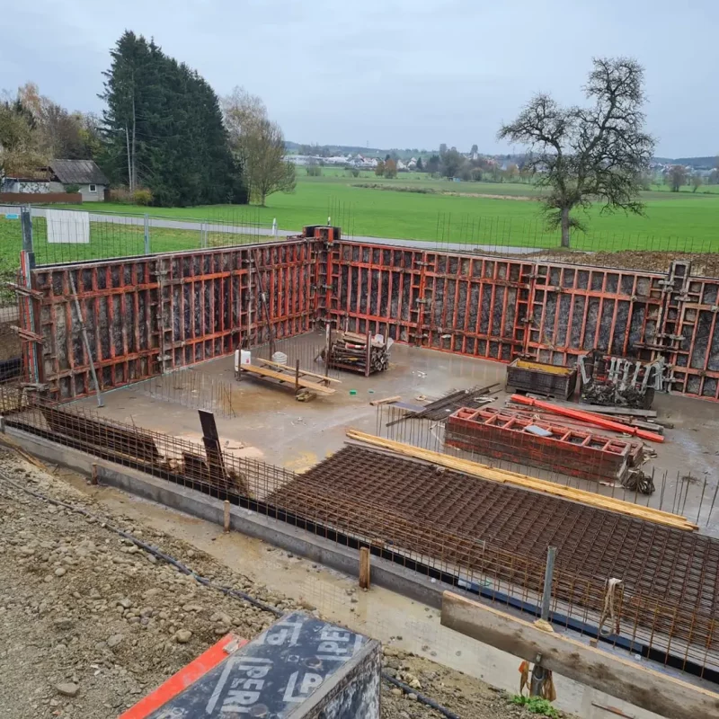 Baustelle mit Schalung und Bewehrung, vermutlich für ein Gebäudefundament.