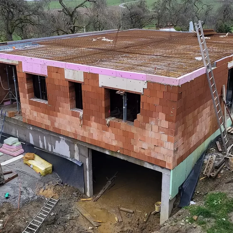Ein im Bau befindliches Haus mit unverputzten Ziegelwänden und ohne Dach.
