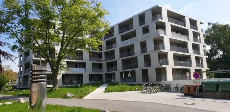 Moderne Wohnung mit Balkonen, Baum, Fahrrädern und fachmännisch ausgeführten Betonarbeiten.